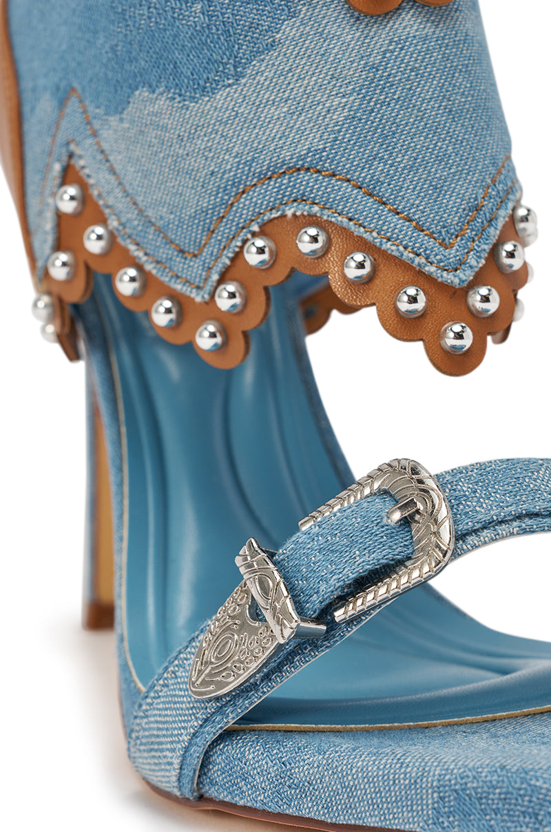 The AZALEA WANG CAPRIZIA DENIM WESTERN NOVELTY STUDDED STILETTO SANDAL features blue denim straps, a silver buckle, brown scalloped leather trim, metallic studs, and a blue insole. 7