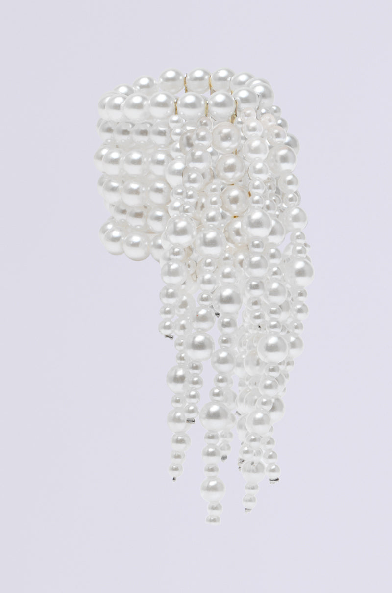 The PEARL VISION STATEMENT BRACELET features a cascade of white pearls in various sizes on a simple light gray backdrop, exuding elegance and luxury. 3