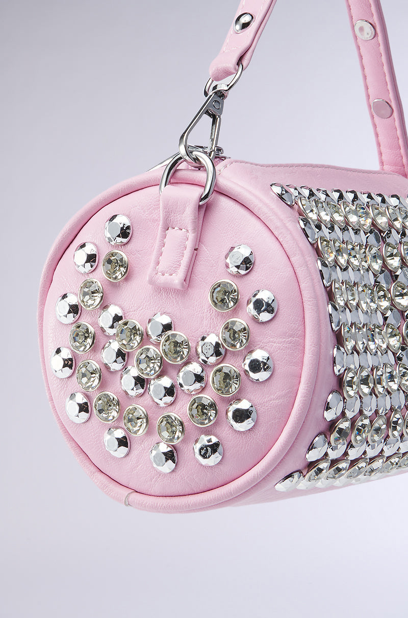 A close-up of the LUXE LIFESTYLE PURSE—a round pink faux leather bag with a strap, featuring large silver studs and sparkling rhinestones for a glamorous touch. Set against a light gray background. 3