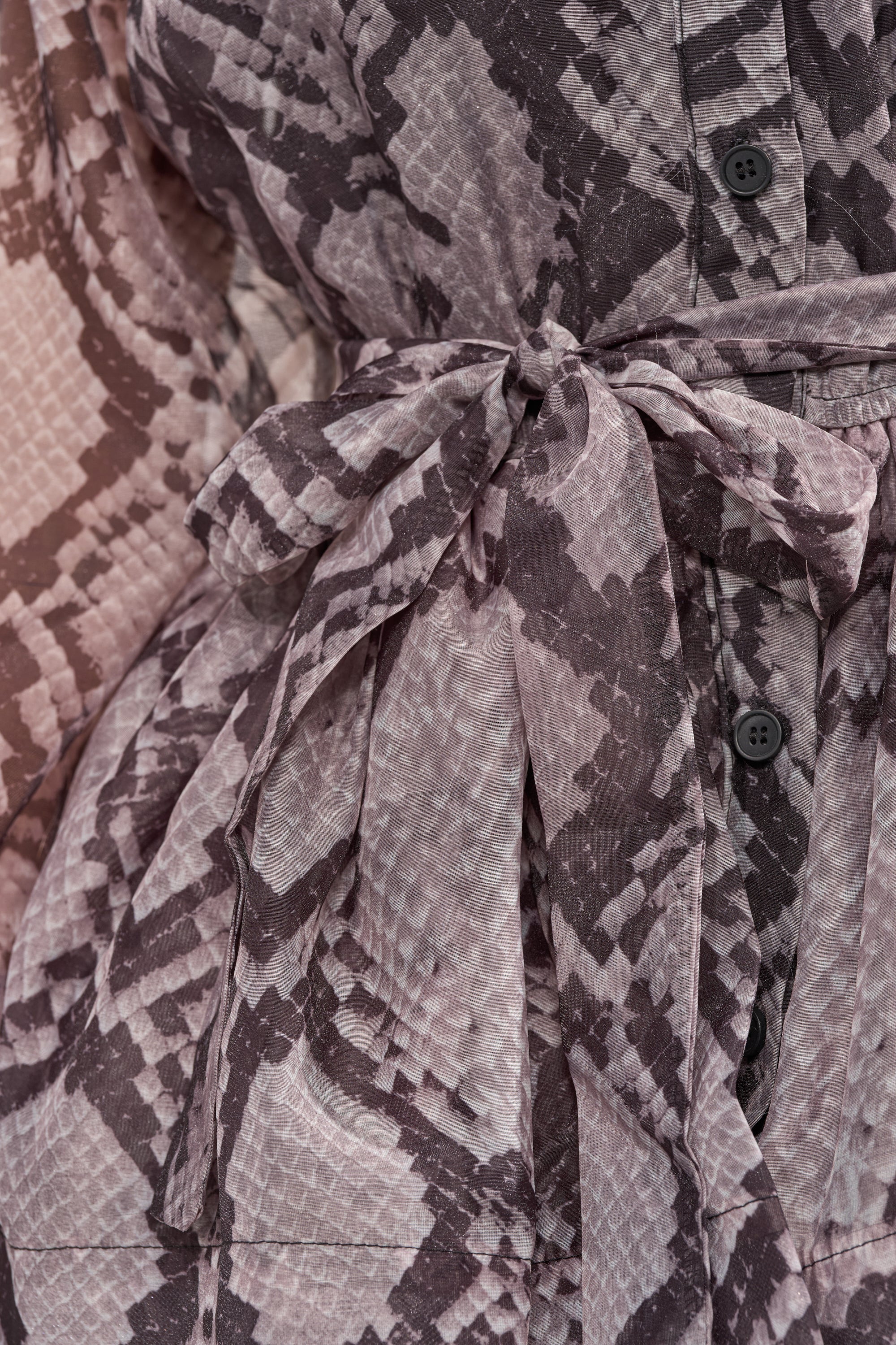 Close-up of the IT GIRL Chiffon Ruffle Mini Dress in Snake, showcasing brown and beige python print, black buttons, and a fabric belt tied at the waist. 6