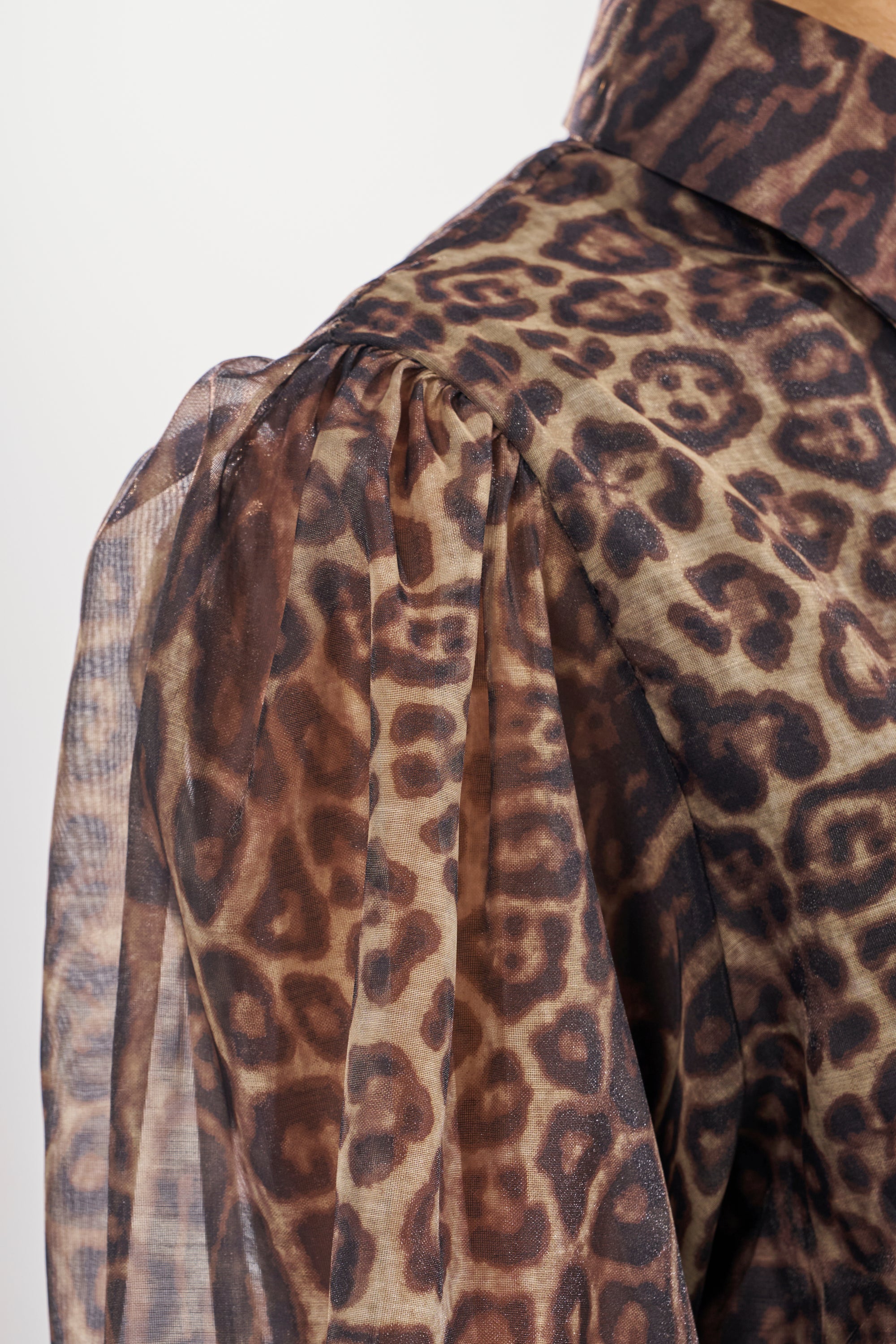 A close-up of the CHICEST OF CHIC LEOPARD PRINT MINI DRESS shows its sheer puff sleeve, lightweight semi-transparent fabric with detailed animal spots, and a structured shoulder for a chic, bold look.
