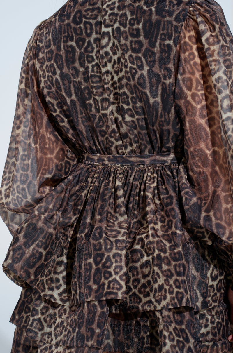 A close-up of a ruffled, layered fabric from the CHICEST OF CHIC LEOPARD PRINT MINI DRESS showcases its elegant and textured sheer fabric in brown and black leopard print, ideal for the bold skater design.