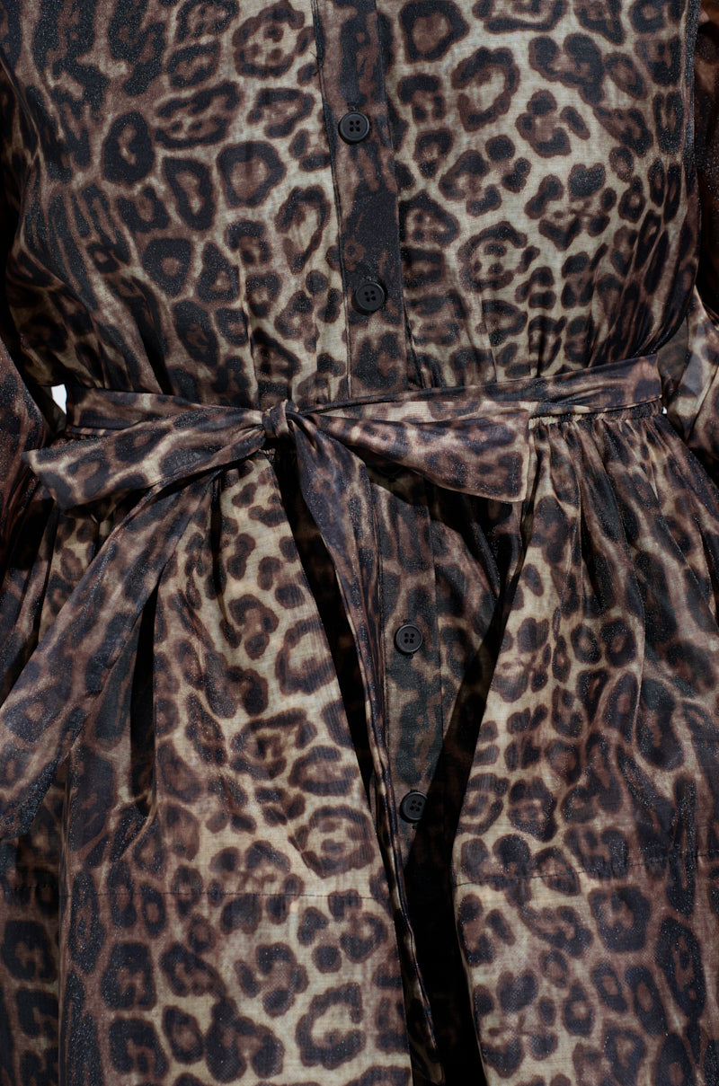Close-up of the "Chicest of Chic Leopard Print Mini Dress" showcasing its tied belt, black front buttons, and leopard spot-inspired textured pattern. The fabric is lightweight and slightly sheer, enhancing its stylish design.