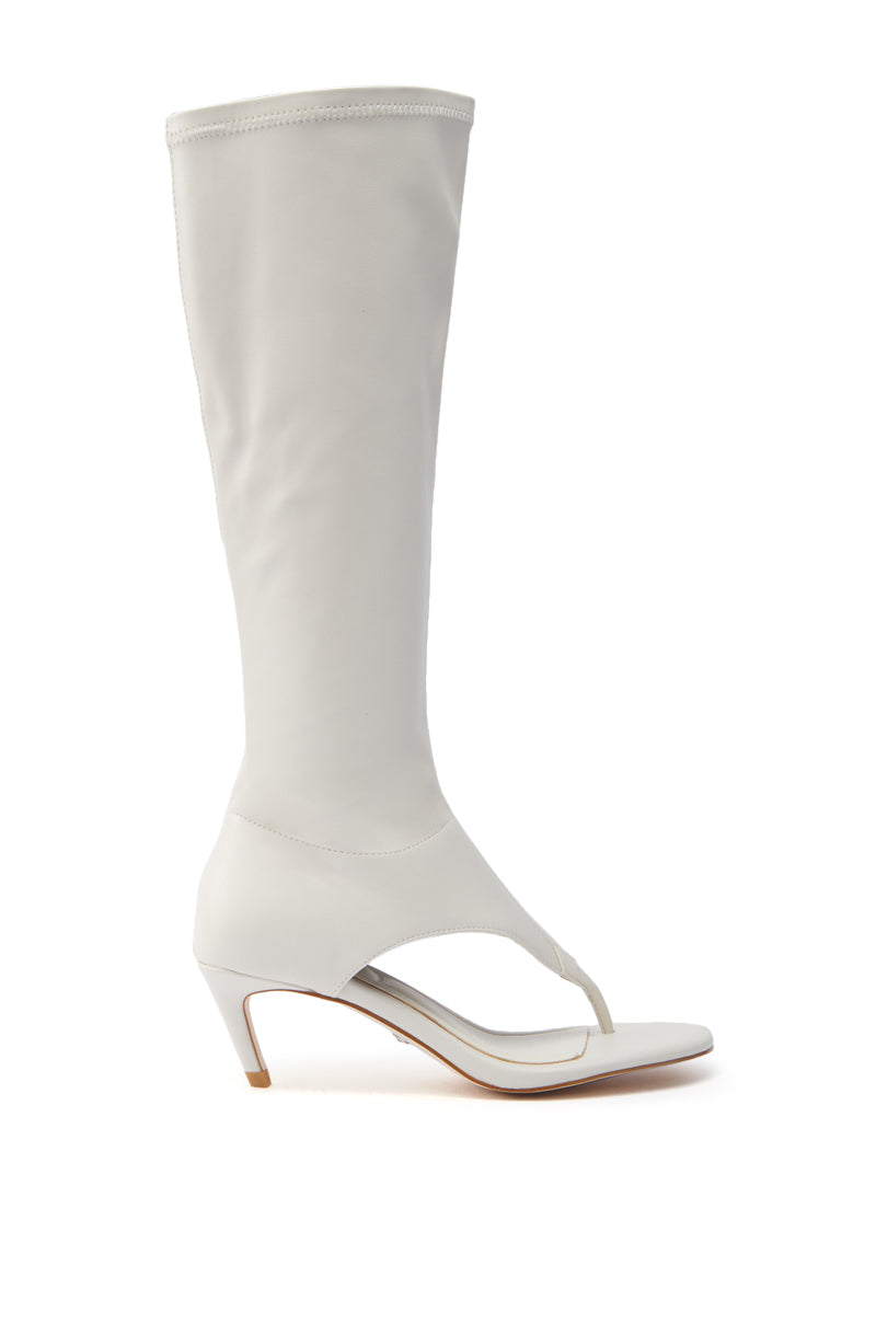 The AZALEA WANG CECILE BONE SANDAL STILETTO is a vegan leather white knee-high boot with an almond thong toe design and mid-height stiletto heel, offering a modern silhouette against a white background.