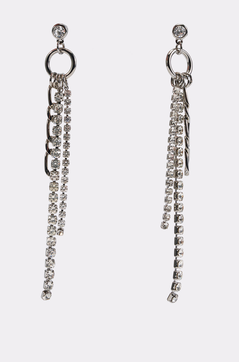 The SILVER BABE DANGLE EARRING features a round stud, a circular loop, and multiple dangling chains embellished with small clear rhinestones for a glamorous accent, displayed against a plain white background.