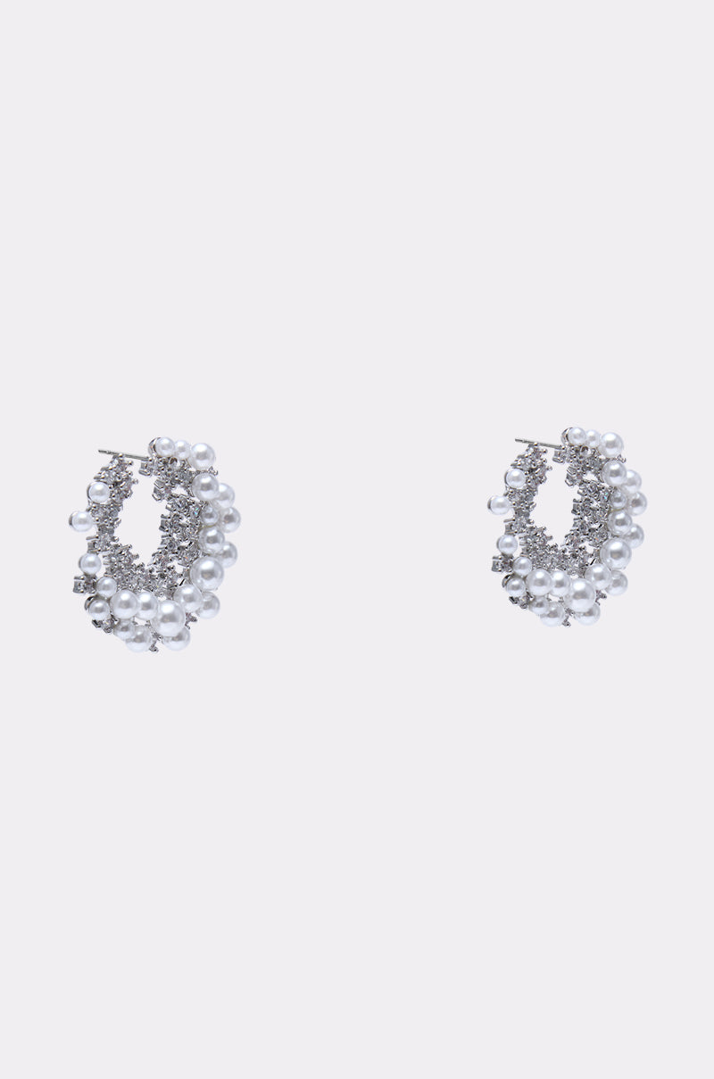 The TRISH EARRING features silver hoops embellished with rhinestones, small white pearls, and sparkling crystals—an eye-catching statement accessory shown against a light gray background. 2