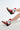 Two legs in AZALEA WANG CHANNING MULTI WESTERN BOOTIE with red and white faux leather, stars, and lightning bolt designs stand gracefully against a plain white background. These booties have angled chunky heels and studded details.