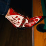 Someone wearing the AZALEA WANG CHANNY MULTI BOOTIE GRAPHIC WESTERN WITH STUDS, featuring star and lightning bolt designs and a chunky heel, rests their foot on the edge of a wooden pool table by a pocket.