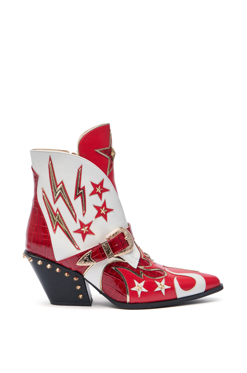 The AZALEA WANG CHANNY MULTI BOOTIE GRAPHIC WESTERN WITH STUDS features red and white faux leather, gold and green lightning bolt and star designs, moon and star motifs, a studded heel, decorative buckle, and a bold chunky black angled heel.