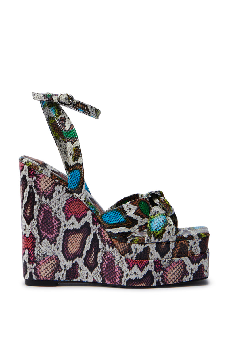 The AZALEA WANG CHARMANDER MULTISNAKE WEDGE SANDAL showcases a vibrant snakeskin print in pink, green, blue, and brown. This stylish sandal boasts an ankle strap and crossover front straps.