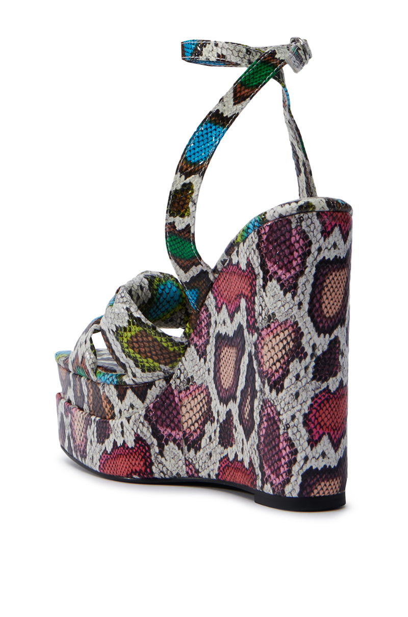 The AZALEA WANG CHARMANDER MULTISNAKE WEDGE SANDAL features a vibrant snakeskin pattern with a high platform and ankle strap, mixing blue, green, pink, and brown shades for a bold fashion statement.