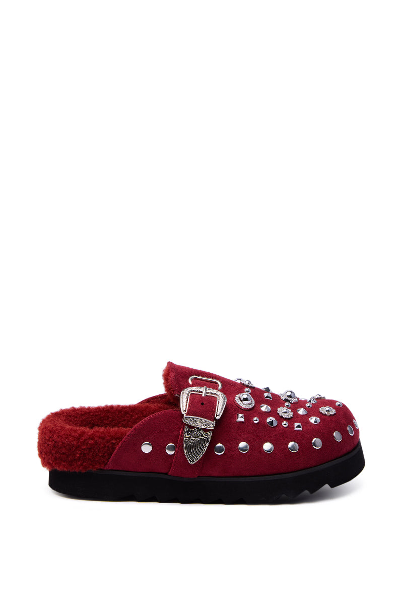 The AZALEA WANG CHATTER BURGUNDY FUR SLIP ON CLOG features a burgundy faux suede upper, black sole, silver studs, a Western-style buckle, eye-catching embellishments, and a plush inner lining for comfort.