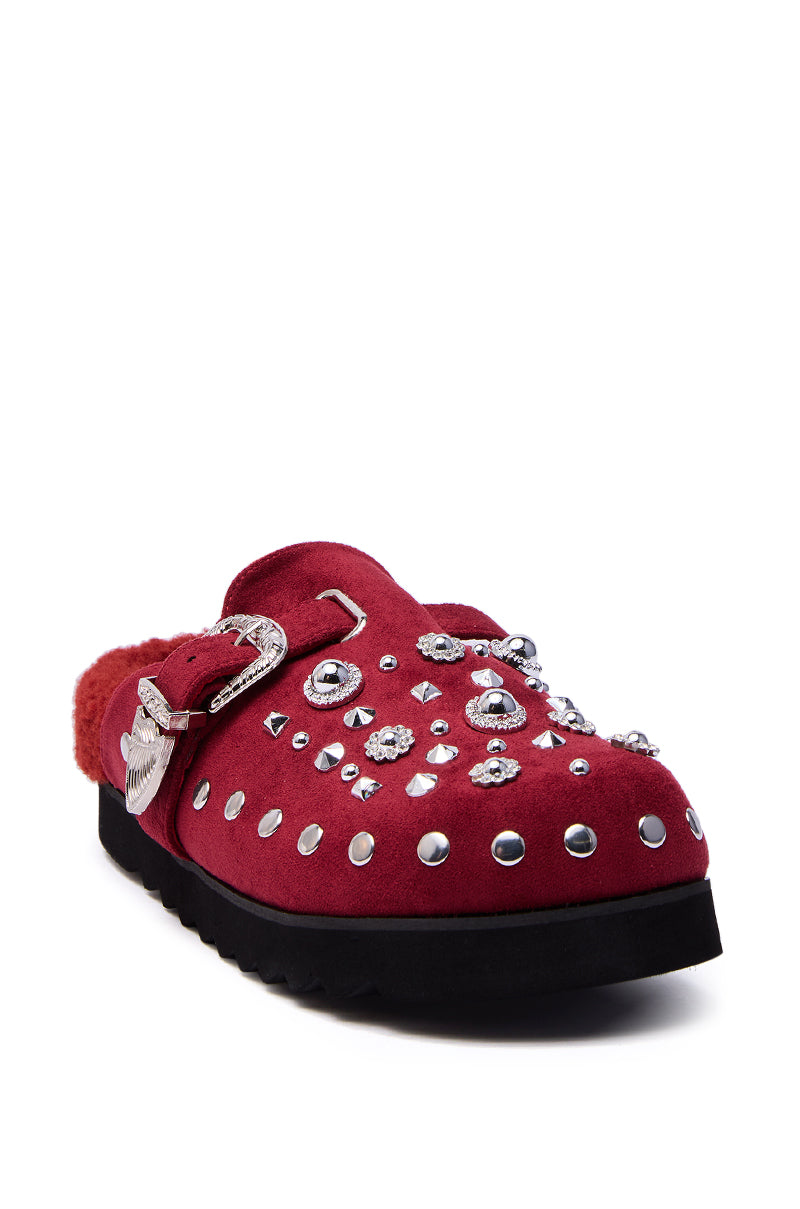 The AZALEA WANG CHATTER BURGUNDY FUR SLIP ON CLOG features burgundy faux suede, a black sole, silver studs and gemstones, a decorative buckle, and cozy sherpa lining.