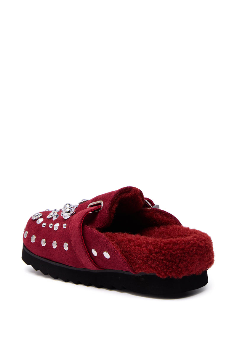 The AZALEA WANG CHATTER BURGUNDY FUR SLIP ON CLOG features a plush burgundy upper with silver studs, rhinestones, and a Western-style buckle for stylish flair, all on a comfy black sole.