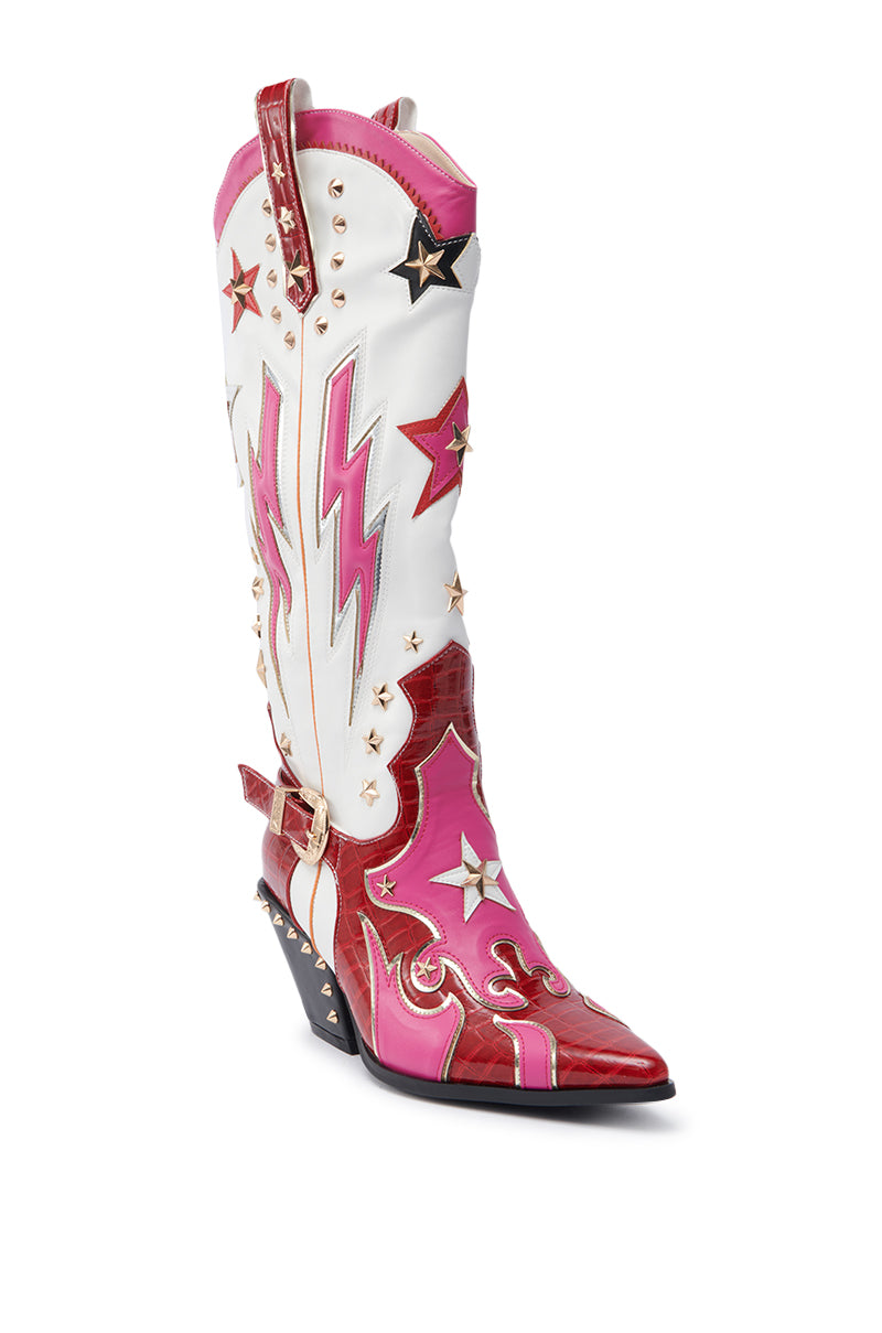 The AZALEA WANG CHEONA RED MULTI WESTERN BOOT is a knee-high faux leather boot in bold red, pink, and white, featuring lightning bolt and star motifs, metallic studs, a pointed toe, and a chunky angled heel for standout style.