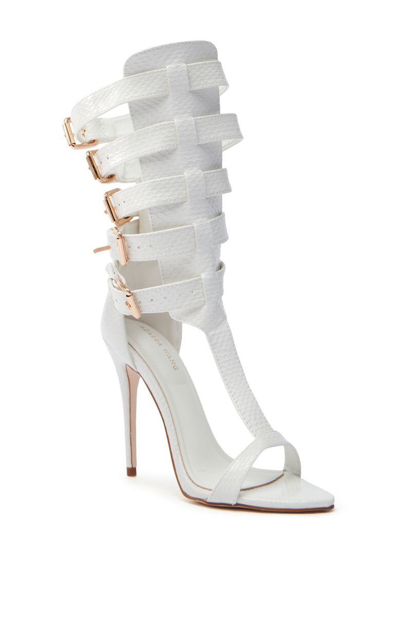 The AZALEA WANG CHERELL WHITE GLADIATOR SANDAL STILETTO features a vegan patent leather design with multiple straps, rose gold buckle accents, and an open toe, all adorned with a delicate textured pattern.