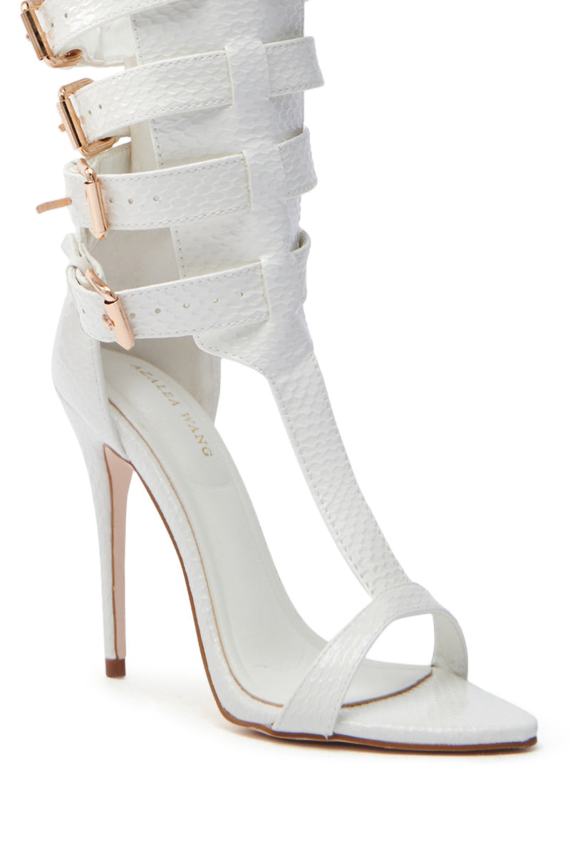 The AZALEA WANG CHERELL WHITE GLADIATOR SANDAL STILETTO features vegan patent leather with a textured finish, multiple ankle straps with gold buckles, and a thin stiletto heel that complements the open-toe design.