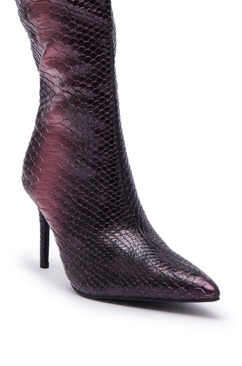 A close-up of the AZALEA WANG CHERICE PURPLE SNAKESKIN STILETTO BOOT, showcasing its knee-high silhouette, pointed toe, and glossy purple and black snakeskin texture.