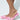 A close-up of a person's lower legs shows them wearing AZALEA WANG CHERINA pink flats with embellishments. These stylish slip-ons feature a mesh design decorated with floral appliques against a light, neutral background.