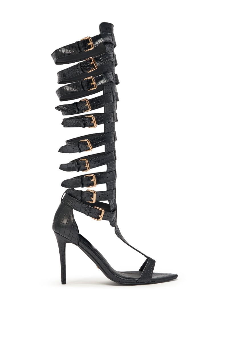 The AZALEA WANG CHERLLI BLACK CROC OVER THE KNEE SANDAL features black croc-embossed faux leather, a stiletto heel, multiple gold buckles, and knee-high straps for a bold, dramatic style. 3