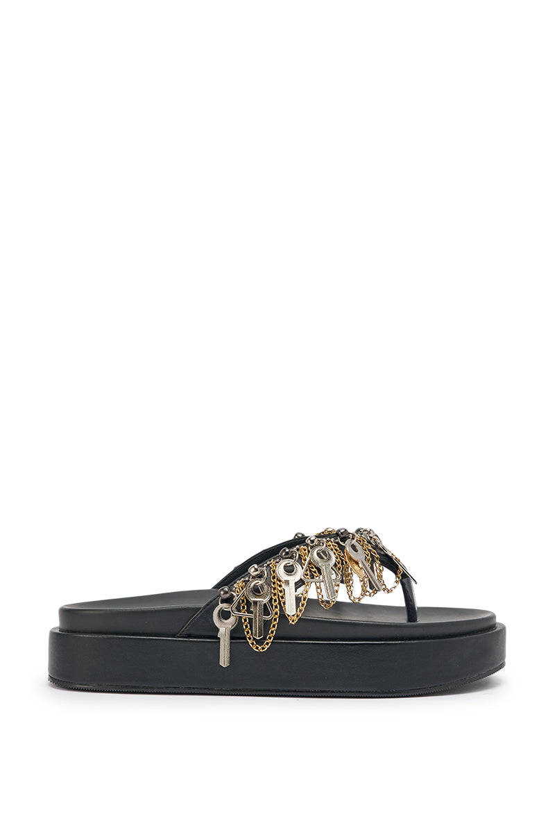 The AKIRA GOLD CHRISTEN BLACK KEY EMBELLISHED NOVELTY PLATFORM SANDAL is a black faux leather thong platform sandal, decorated with multiple silver and gold metallic key and chain charms. 5