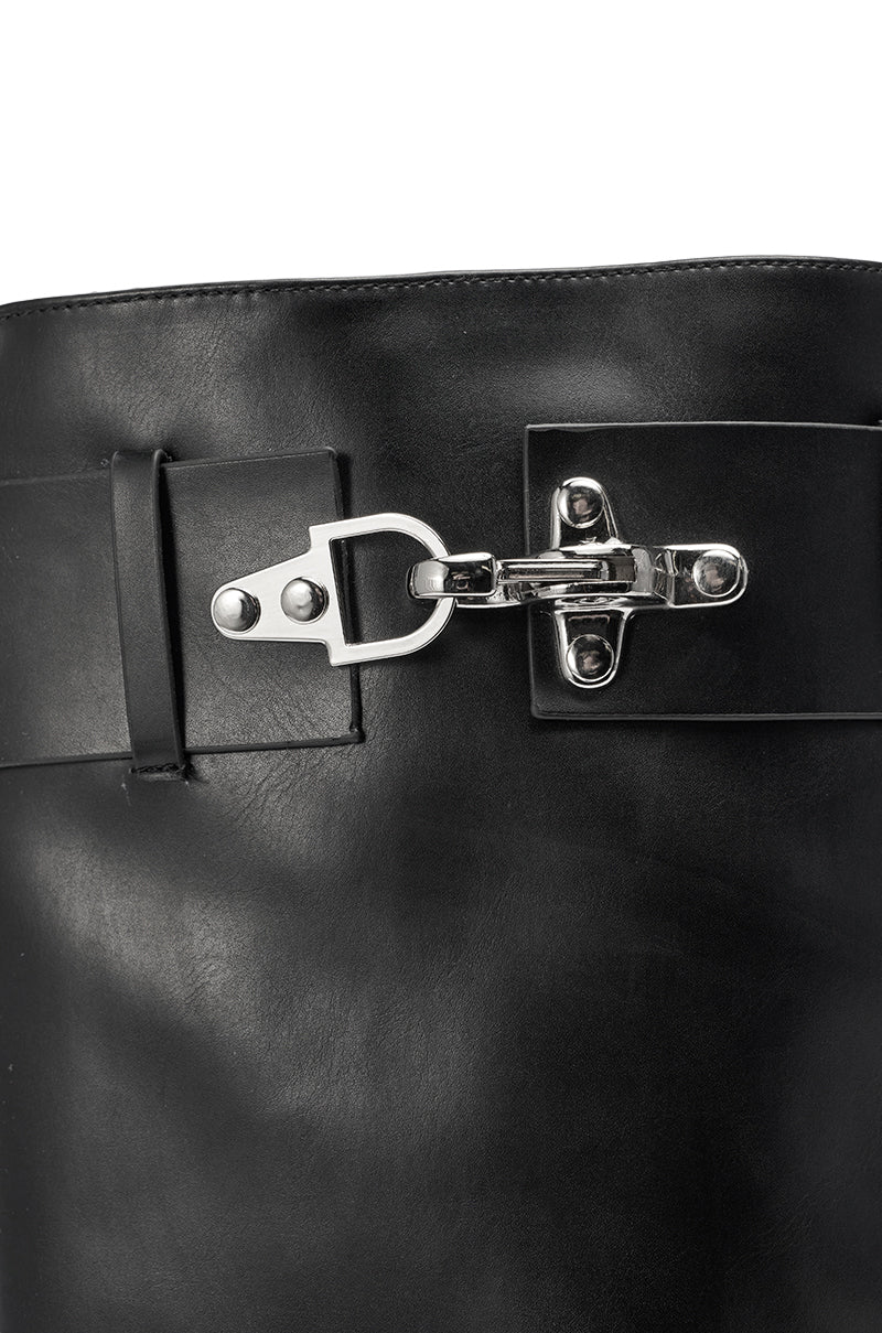 A close-up of the AZALEA WANG CHRONO Black Metal Heel Boot, featuring a pointed toe, silver metal buckle and clasp on the shaft, smooth matte leather, shiny hardware, and a sleek geometric heel. 7