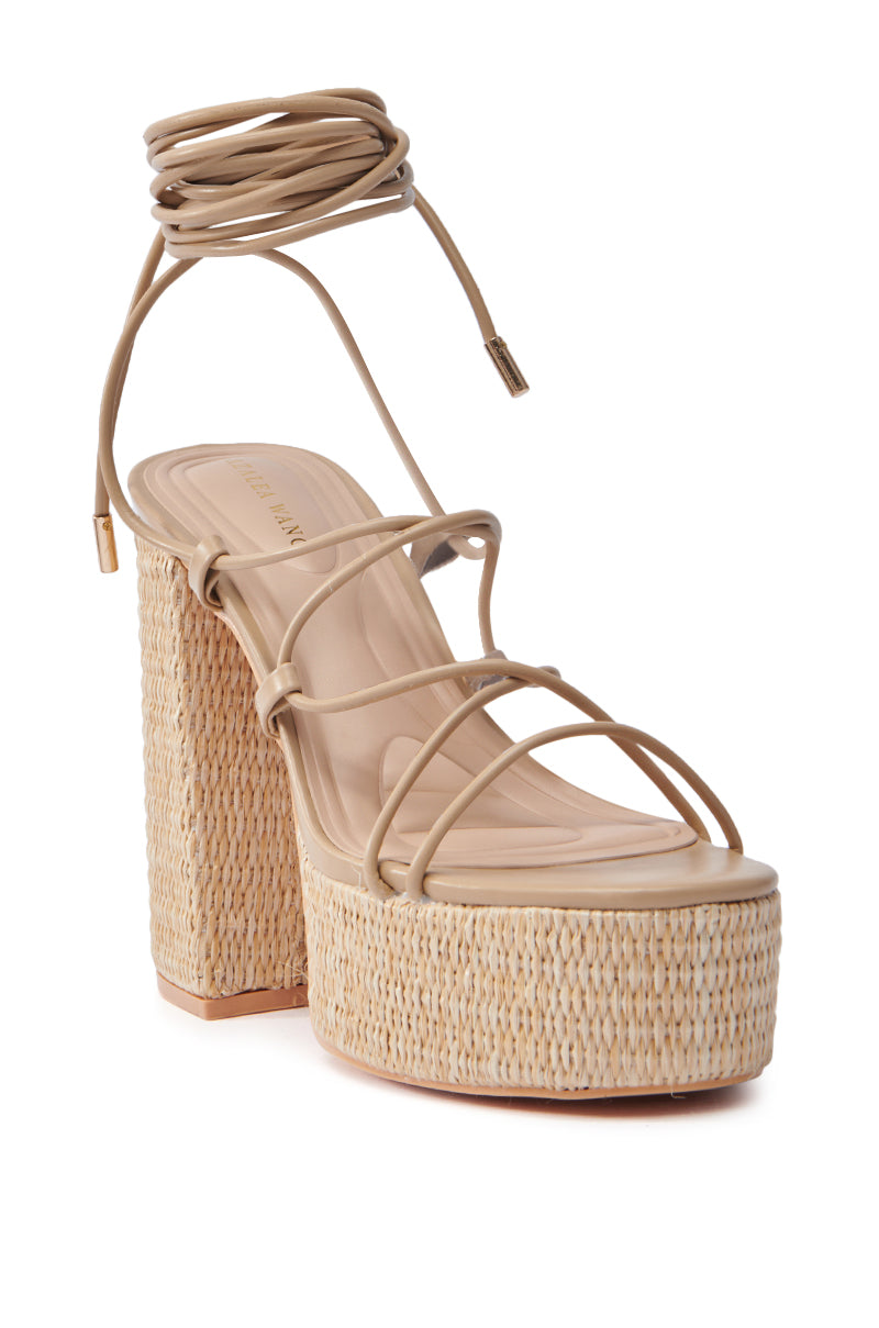 The AZALEA WANG CIERRA BEIGE STRAPPY RAFFIA PLATFORM SANDAL features a chunky heel, thin straps across the foot, and a wraparound ankle tie. It boasts a comfort cushion insole for style and comfort, with the sole and footbed in a cohesive light tan hue.