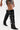 A person wears AZALEA WANG CINZIA BLACK CROC BUCKLE WEDGE BOOT—shiny, over-the-knee with silver buckles and straps—paired with metallic lace-up shorts against a plain white background.