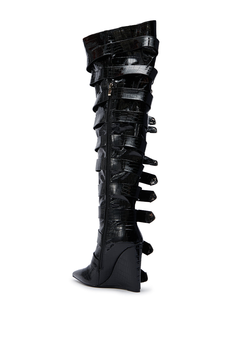 The AZALEA WANG CINZIA BLACK CROC BUCKLE WEDGE BOOT features a glossy black croc finish, knee-high shaft, bold buckle straps, a pointed toe, and side zipper for modern style.