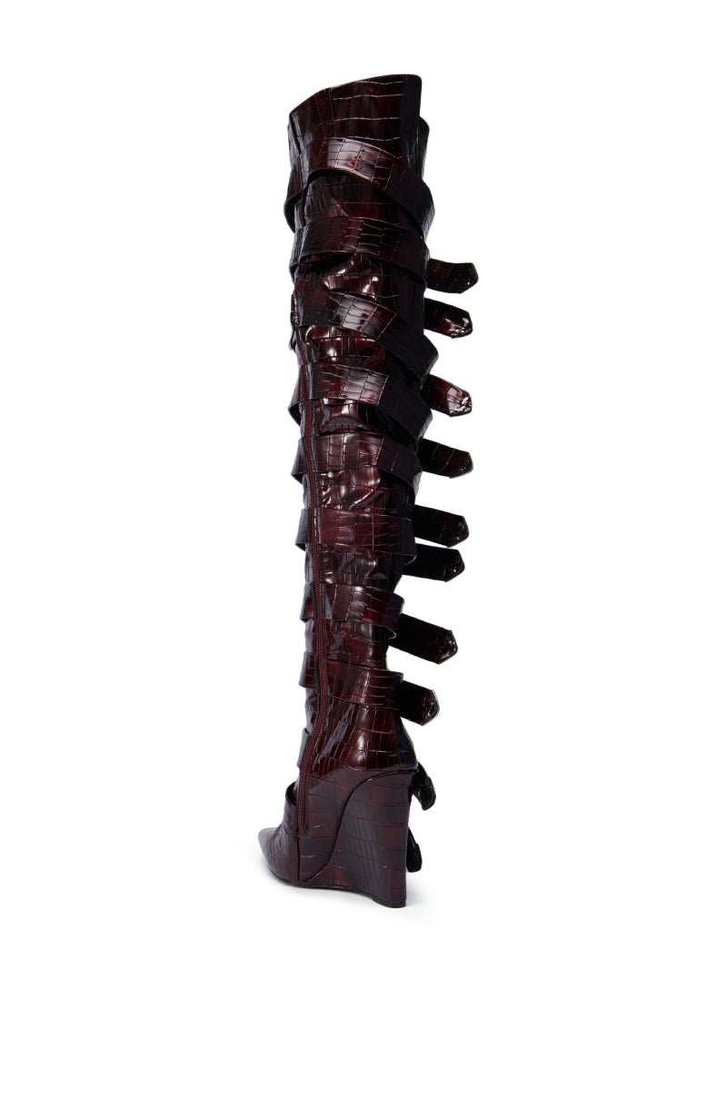 The AZALEA WANG CINZIA RED WEDGE BOOT is showcased against a plain white background, featuring a tall, deep burgundy color with a faux crocodile leather texture and several adjustable buckle straps along the side.