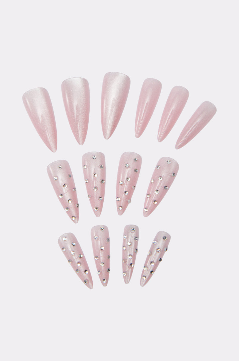 GIRLY VIBES FALSE NAILS offers long, almond-shaped nails in pink with shimmery finishes, gemstone detailing, and accents of small silver rhinestones, all beautifully arranged against a white background.