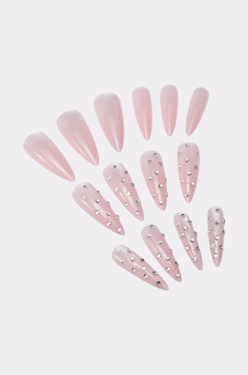 GIRLY VIBES FALSE NAILS: A long, almond-shaped set in light pink with a mix of plain and gemstone-detailed nails featuring small silver rhinestones, all elegantly displayed on a light background.