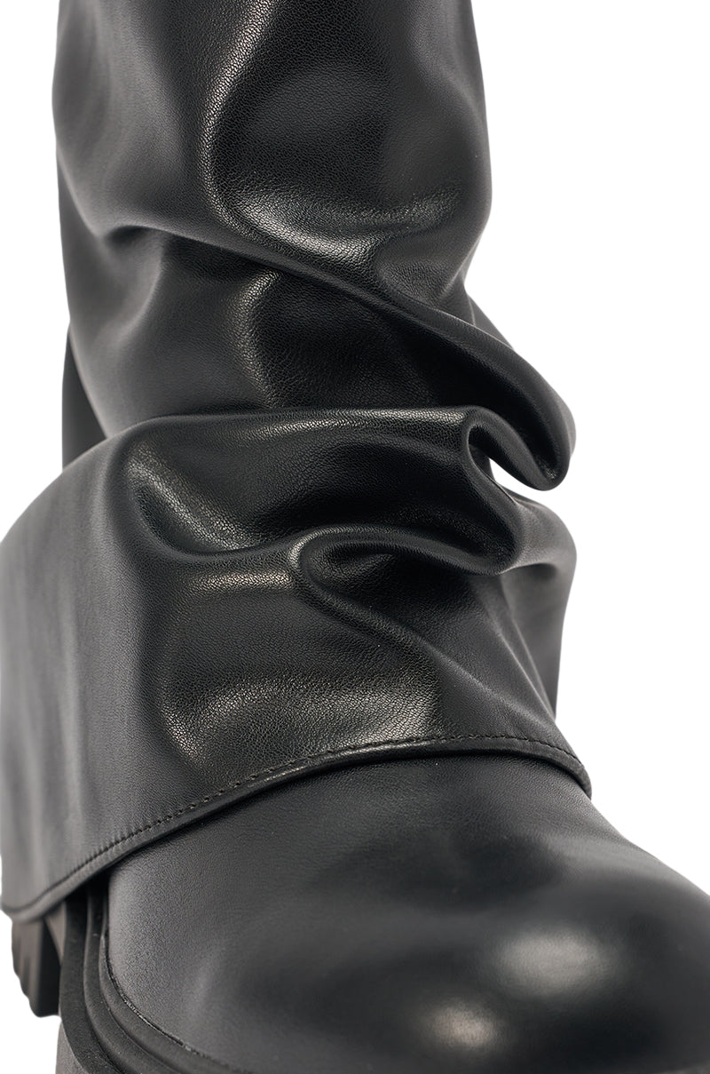 Close-up of the AZALEA WANG CLARKE BLACK PU SLOUCHY SHORT SHAFT COMBAT BOOTIE featuring a black faux leather fold-over shaft, ruched slouchy design around the ankle, and a smooth, rounded toe. 7