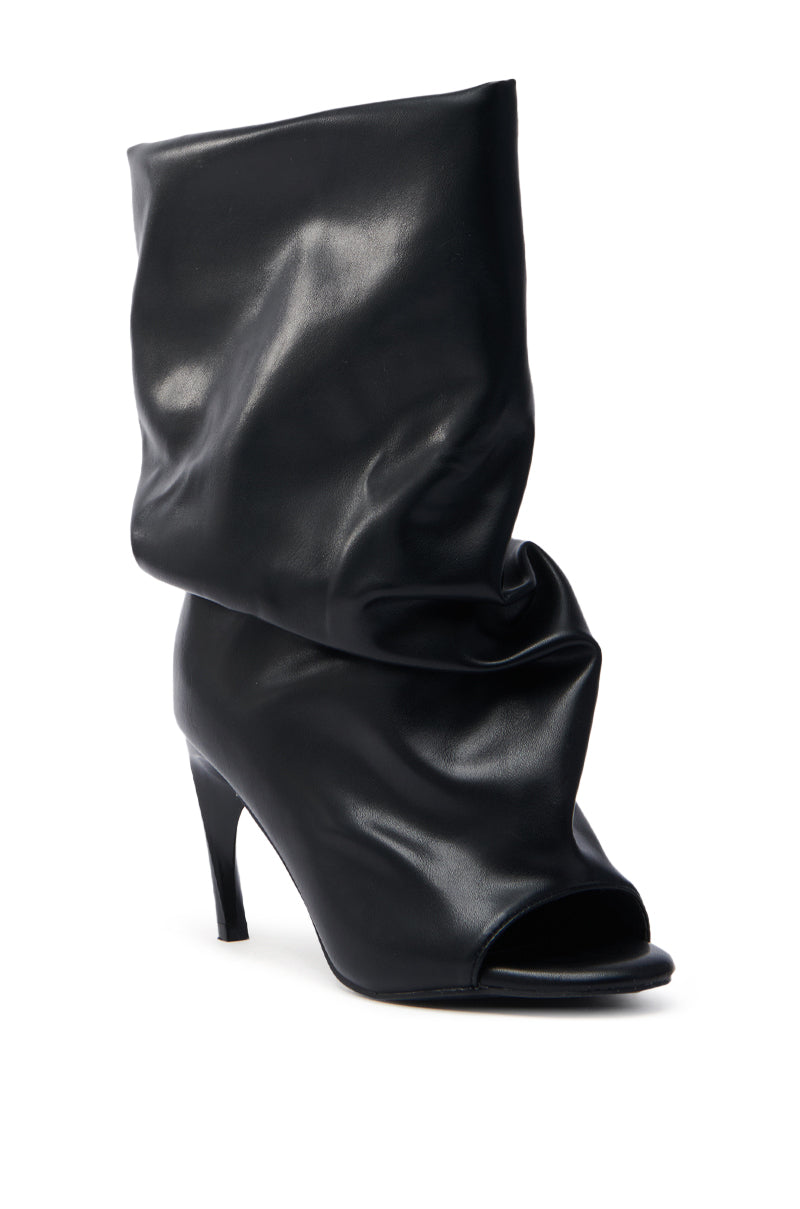 The AZALEA WANG CLASSIE BLACK OPEN TOE BANANA HEEL BOOTIE is a stylish high-heeled shoe with a slouchy faux leather design, featuring a mid-height banana heel. The soft, slightly shiny material adds a modern touch.
