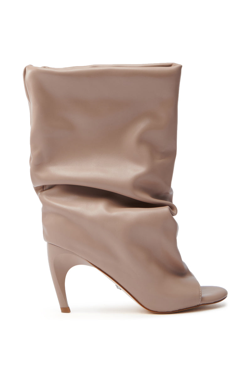 The AZALEA WANG CLASSIE NUDE OPEN TOE BANANA HEEL BOOTIE showcases a taupe faux leather design with an almond peep-toe. Sitting against a white backdrop, its ankle-high slouchy silhouette is enhanced by a slender sculpted banana heel for a stylish touch.