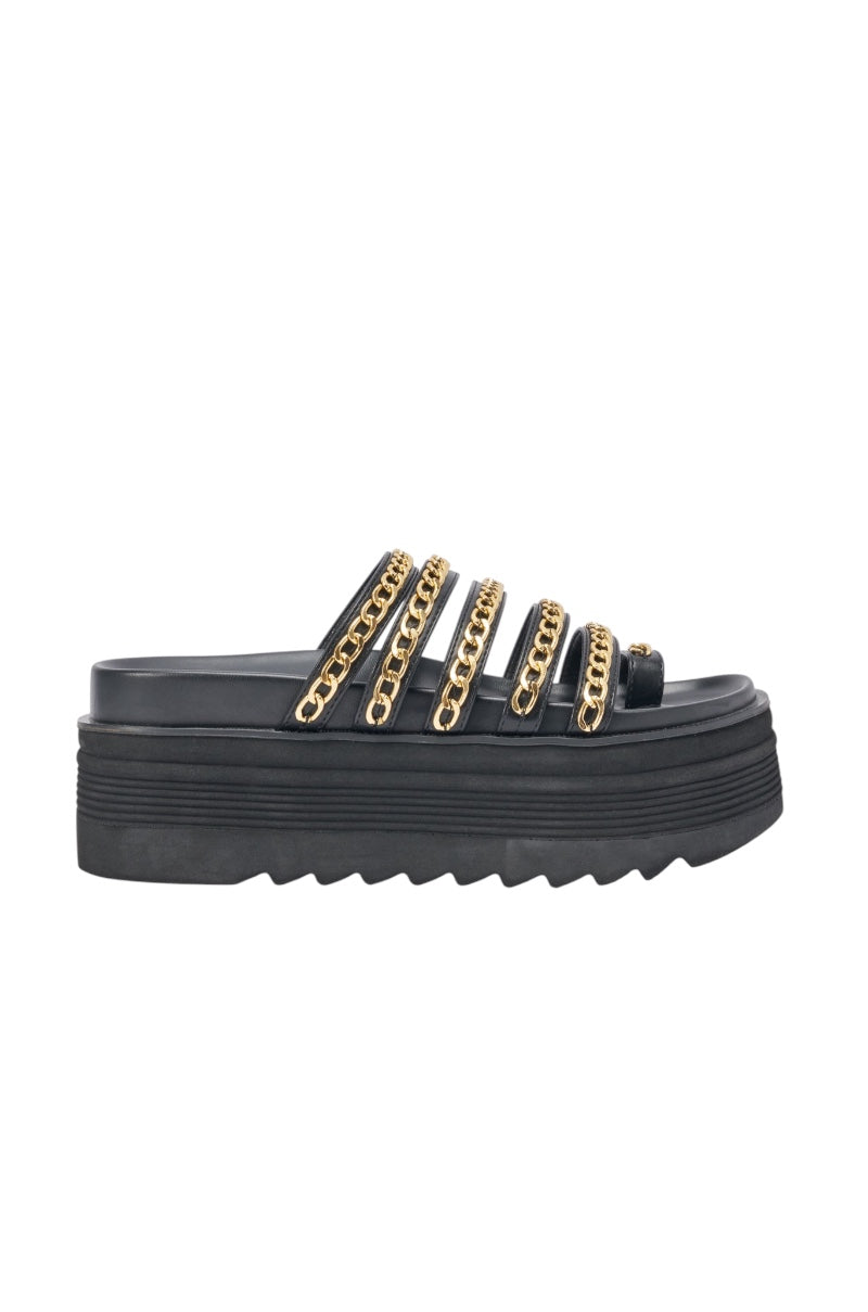 The AKIRA CLEMENTE GOLD CHAIN DETAIL FLATFORM SANDAL is a black faux leather flatform with five horizontal straps featuring gold chain accents and a thick ridged sole. 3