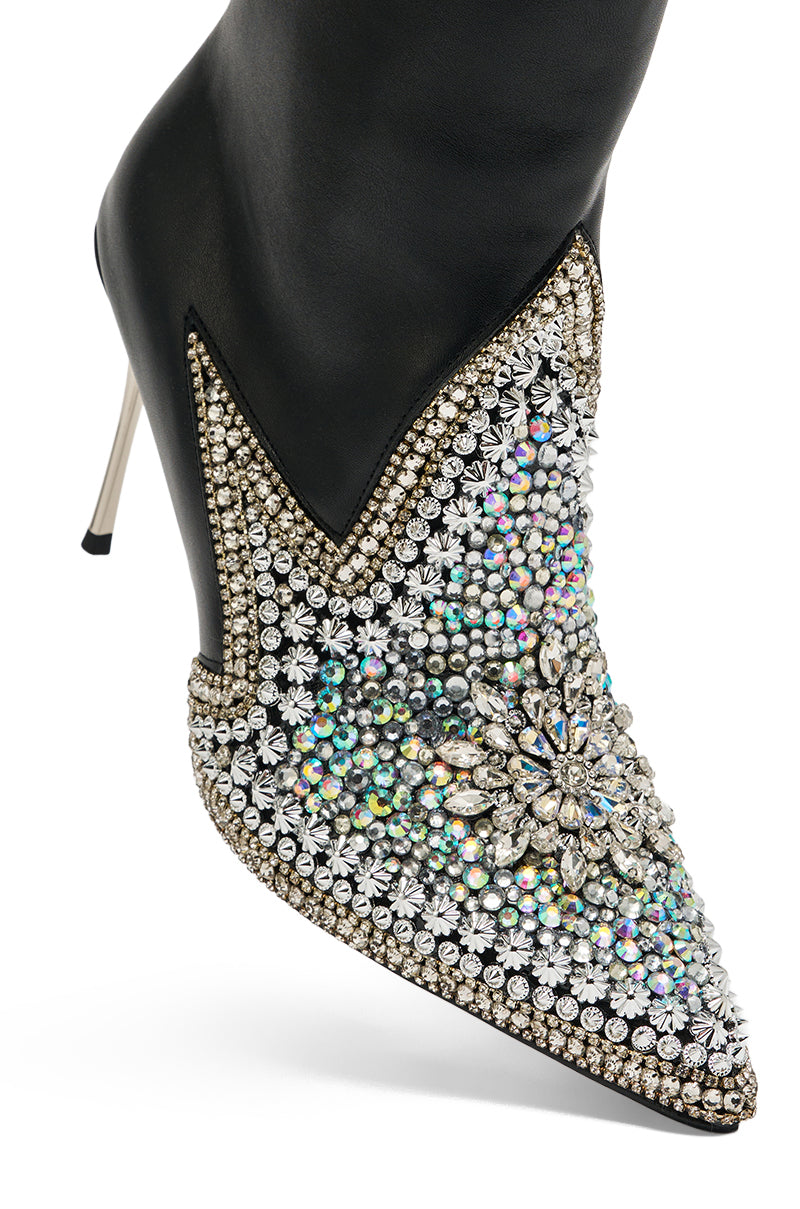 The AZALEA WANG CLINEQ EMBELLISHED RHINESTONE STILETTO BOOTIE showcases black faux leather, a pointed toe, sparkling rhinestones and crystals, a large jeweled flower accent, and a bold metallic silver stiletto heel.
