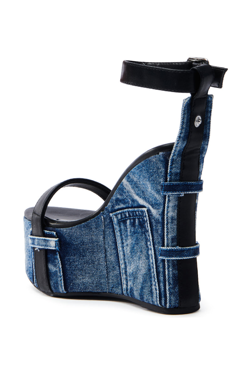 The AZALEA WANG CLIO DENIM SANDAL is a chic denim sandal with a high wedge heel, black leather accents, thick platform sole, and sleek black ankle strap. It mimics jeans with faux pockets and belt loops for added style.