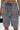 Wearing the SHAGGY BERMUDA SHORT in a high-rise fit with black and white textured ruffles and drawstring waist, a person holds a small black handbag; only their lower torso and upper legs are visible.