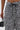 A person wears the AKIRA Label SHAGGY BERMUDA SHORT in a high-rise, textured black-and-white style, holding a small black handbag with rhinestone-accented handle. Image is cropped to highlight their waist and hand.