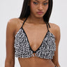 A woman with straight, long hair wears the SHAGGY BRALETTE, a black and white textured halter neck bikini top. She stands against a plain light background, looking directly at the camera with a neutral expression.