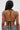 A woman seen from behind wears the SHAGGY BRALETTE, a black and white halter bikini-style top tied at her neck and back. Her long, straight hair falls over one shoulder, revealing a small tattoo on her right shoulder blade.