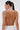 A woman with a sleek ponytail is shown from the back, wearing the RUBY QUEEN RHINESTONE BLOUSE, featuring metallic and pearl shoulder details, chainlink draping across her upper back, and a large tasseled earring.