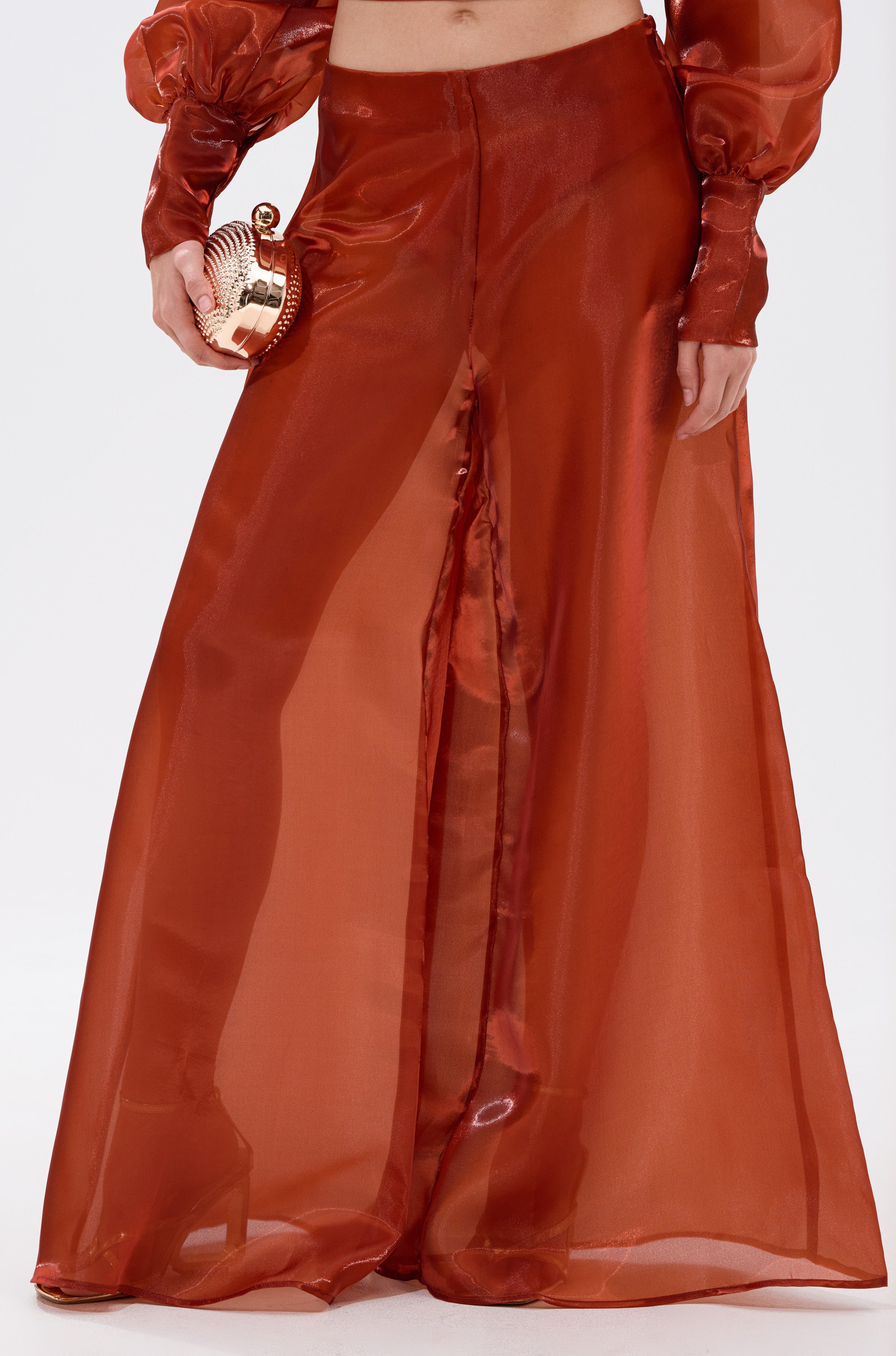 Wearing FEELING FREE CHIFFON PALAZZO PANT with a high-rise fit, paired with a matching long-sleeve top, holding a metallic shell clutch, and standing in high heels. 0