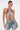 A woman with slicked-back hair models the SHAKE IT FOR ME BABY BEADED BLOUSE, a beaded halter top with a scalloped silhouette and silver chains, paired with distressed light blue lace-up jeans against a white background.