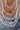 A close-up of a person wearing the SHAKE IT FOR ME BABY BEADED BLOUSE, featuring sparkling clear, silver, and gunmetal seed beads draped over their bare torso, partially covered by light blue denim jeans.