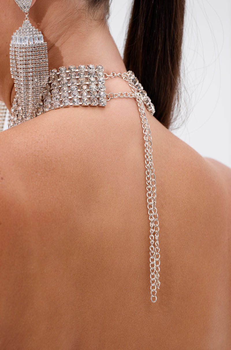Close-up of a woman's bare back, featuring a sparkling rhinestone choker, dramatic tassel earring, and the ALL EYES ON ME HALTER BLOUSE—a dazzling crystal halter top that catches the light.