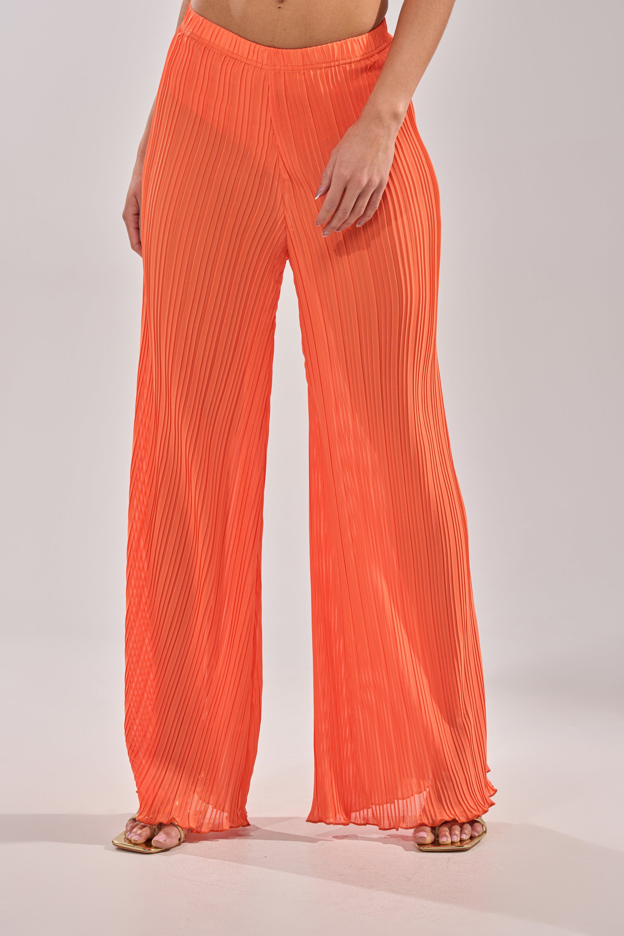 Wearing the CRUSHIN ON YOU PALAZZO PANT in bright orange with open-toe sandals against a light background—an effortless addition to any vacation wardrobe. 1