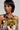 A woman wearing a shimmering metallic gold dress accessorizes with the ALL NIGHT LONG SEQUIN NECKLACE, which features large gold discs, standing against a plain background. Her hair is styled to one side, enhancing her elegant and confident pose.
