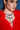 A woman in a vibrant red feathered outfit wears the PRETTY IN PEARLS NECKLACE—a bold, layered pearl and crystal piece—as she gazes to the side against a blue background.